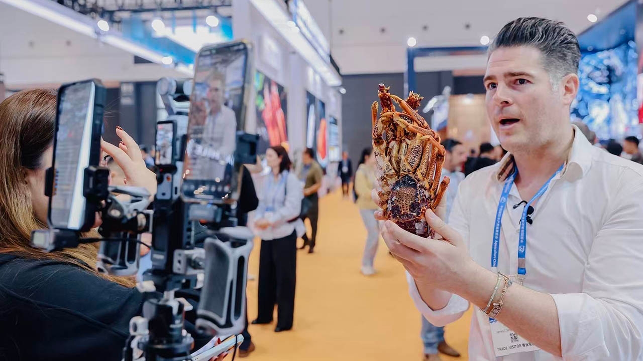 Person holding a lobster at an Expo while being filmed