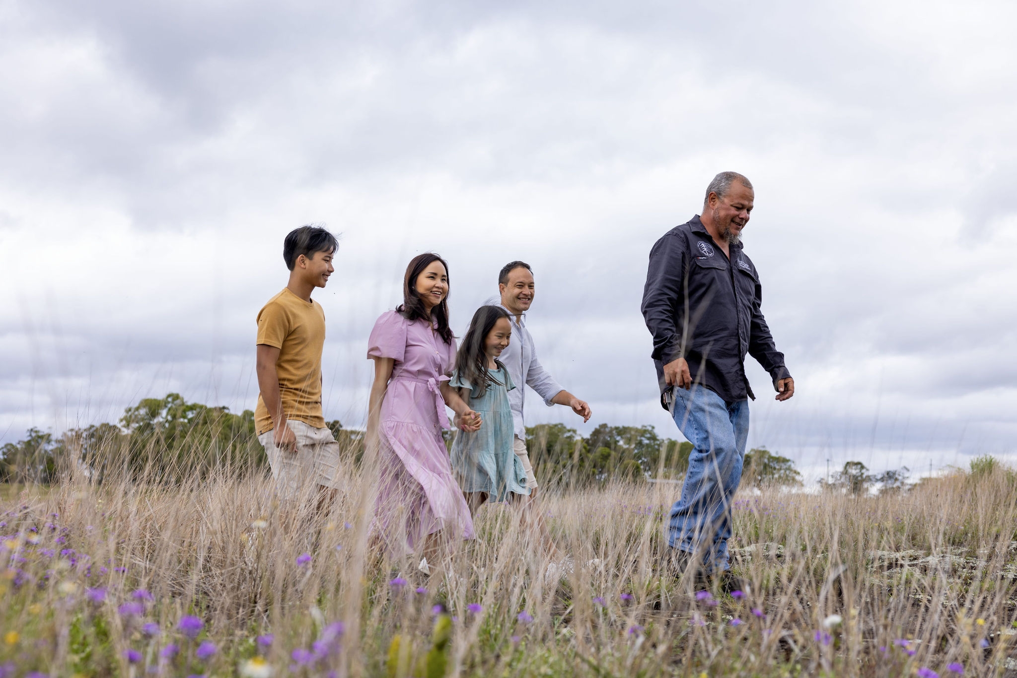 A group of people walking through long grass.