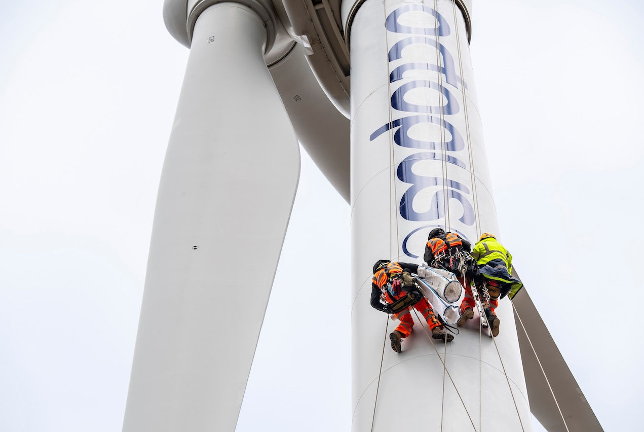 Three people climbing wind turbine