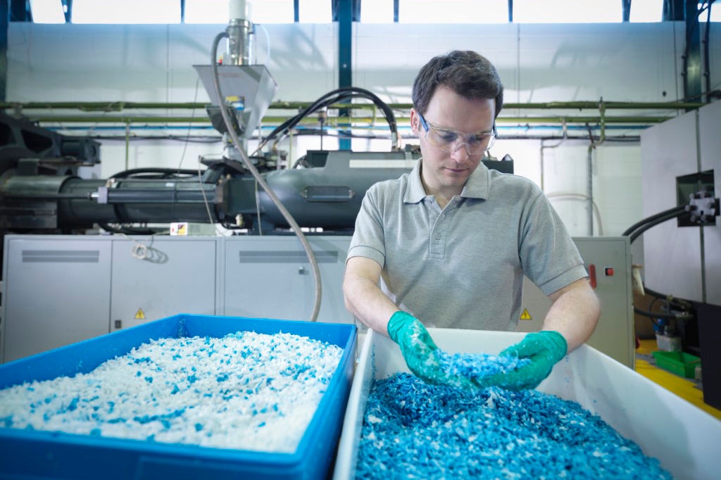 Worker inspecting recycled plastic in plastics factory