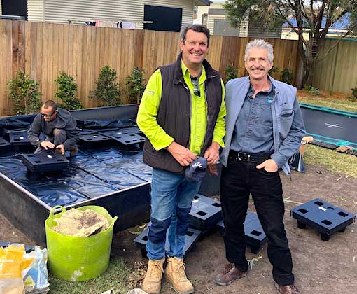Two men standing in front of a ground-level wicking bed.