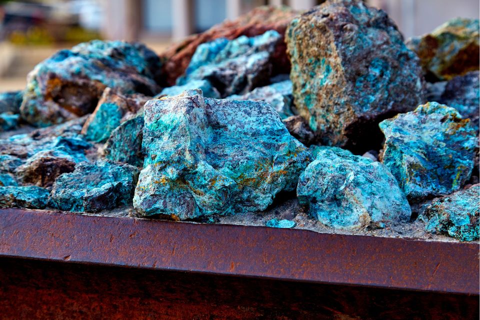 Blue and brown chunks of copper ore mineral rocks in an iron barrel.