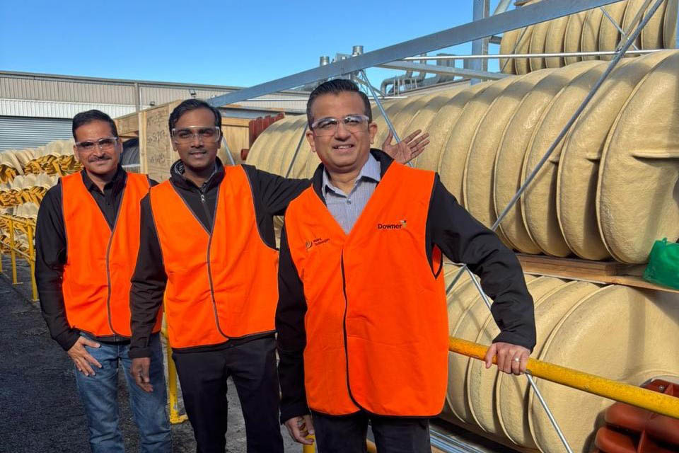 3 men wearing high visible vests standing in front of spiral separators