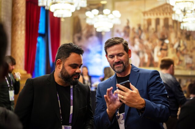 Two men in suits using the EventsAir app in a conference room.
