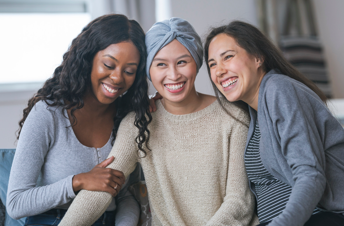 Three women sitting together, comforting the woman in the middle.