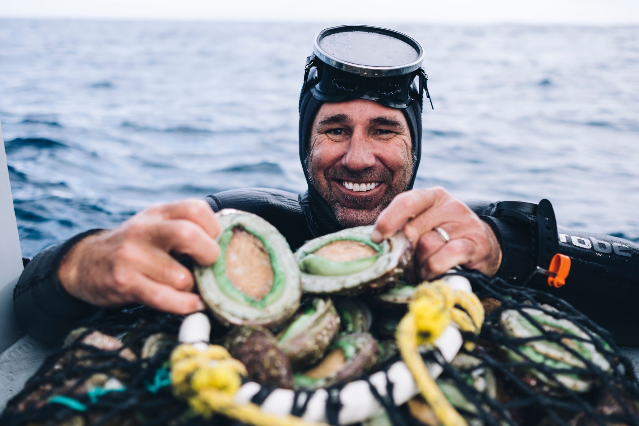 Diver proudly showing green lip abalone in a net