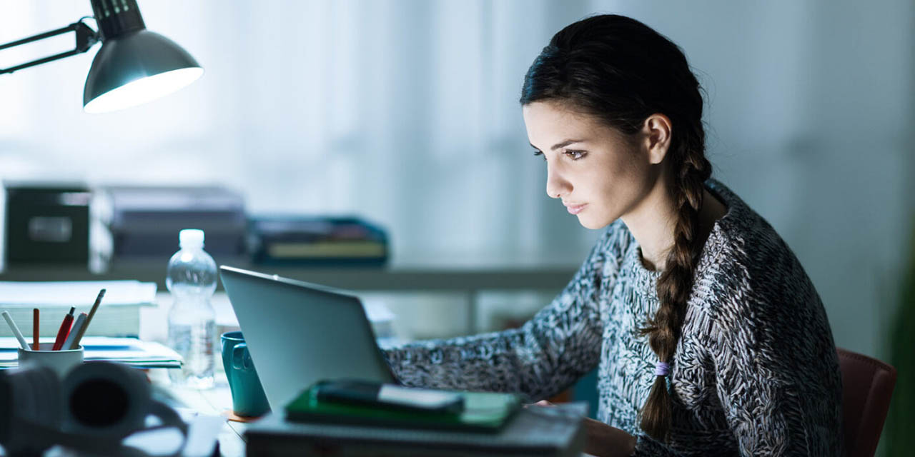 Female student sitting at a desk working on a laptop computer