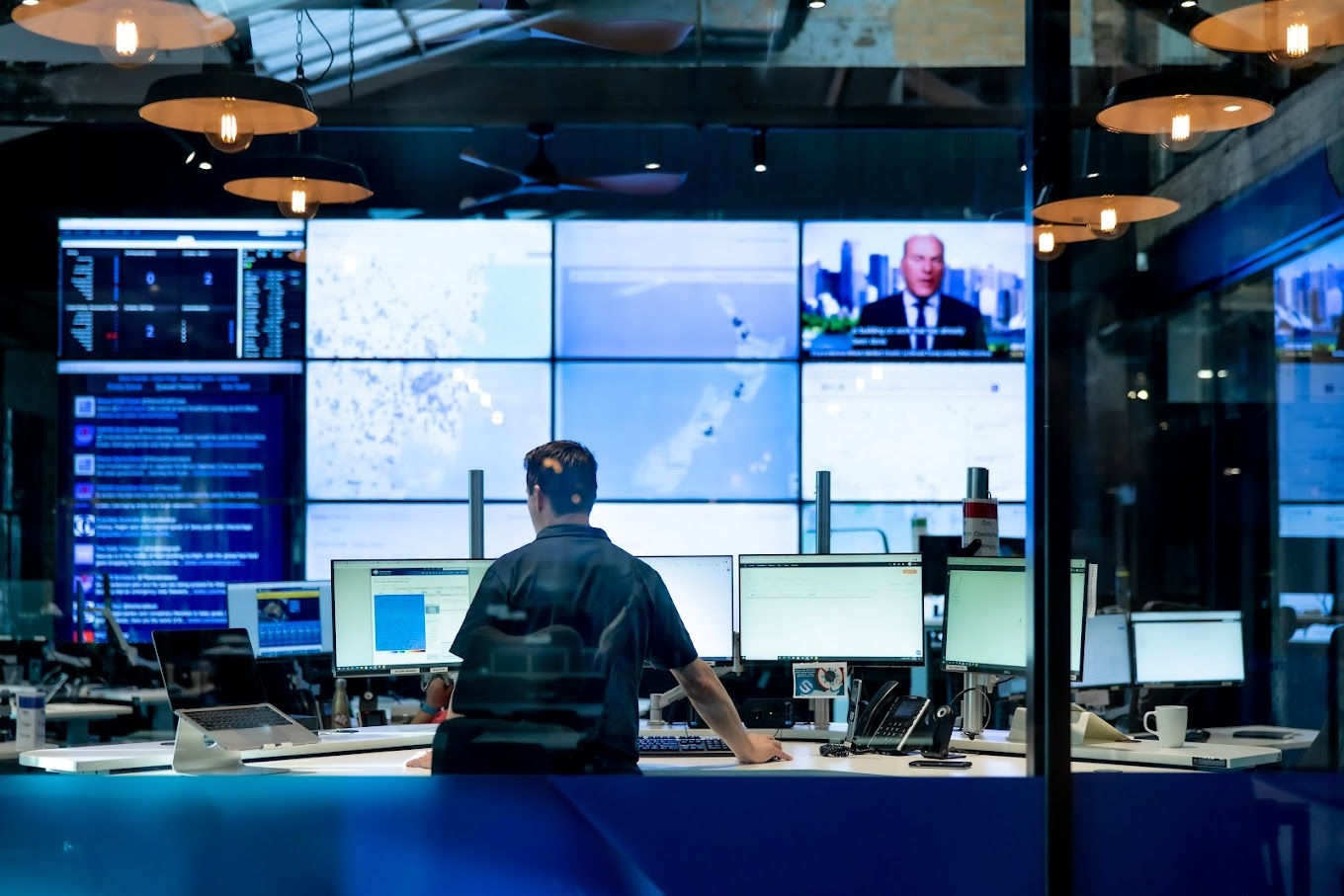 A man standing in front of a bank of computer screens