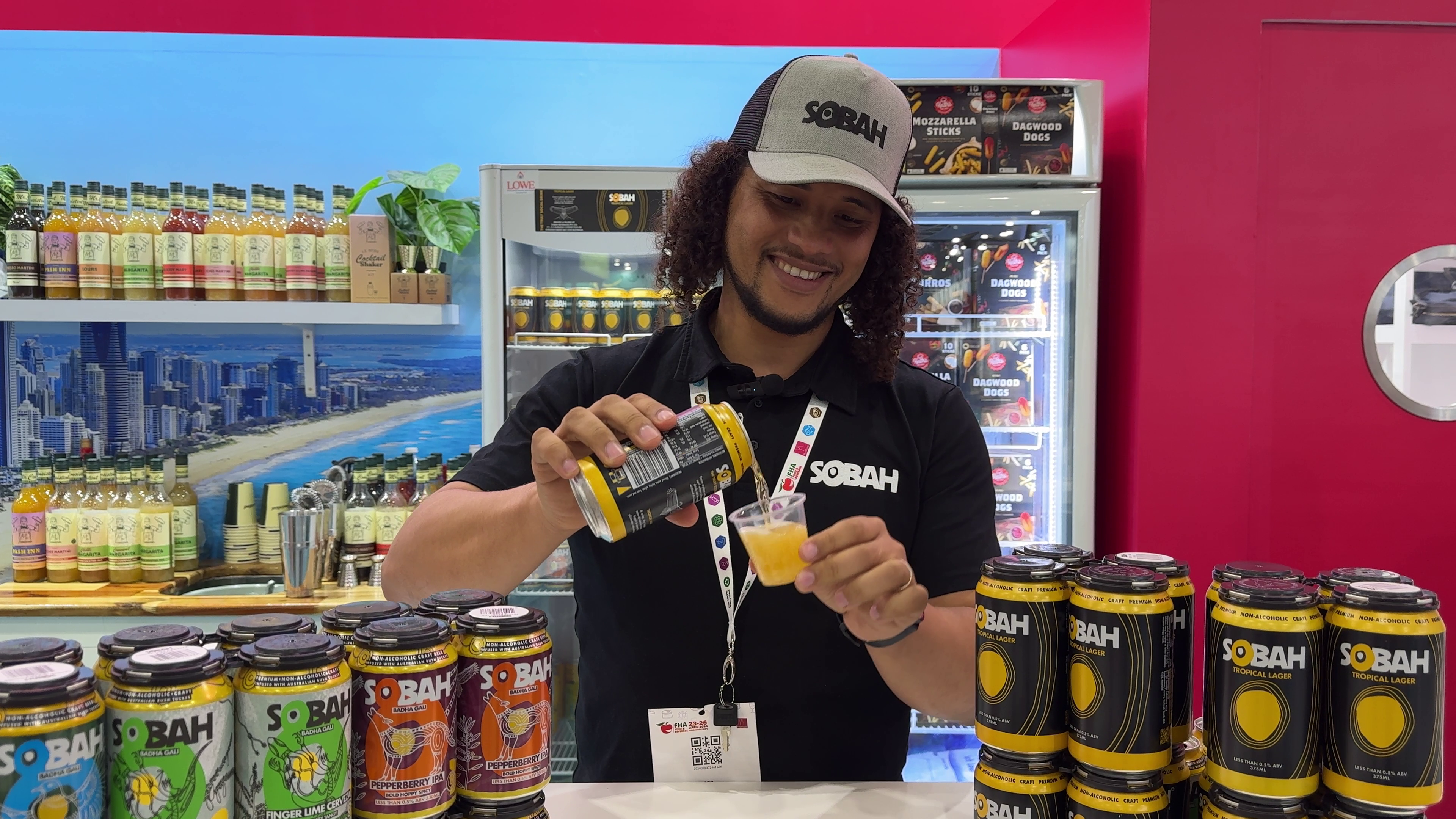 A man pouring a yellow beverage from a can into a small plastic cup.